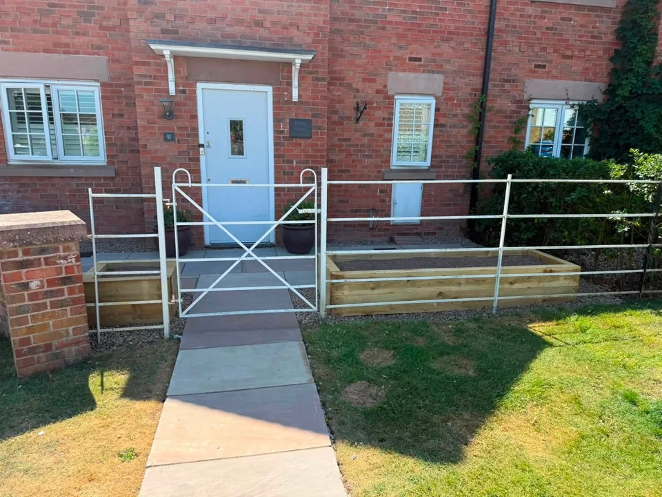 Sandstone front path with white railings and sleeper planters