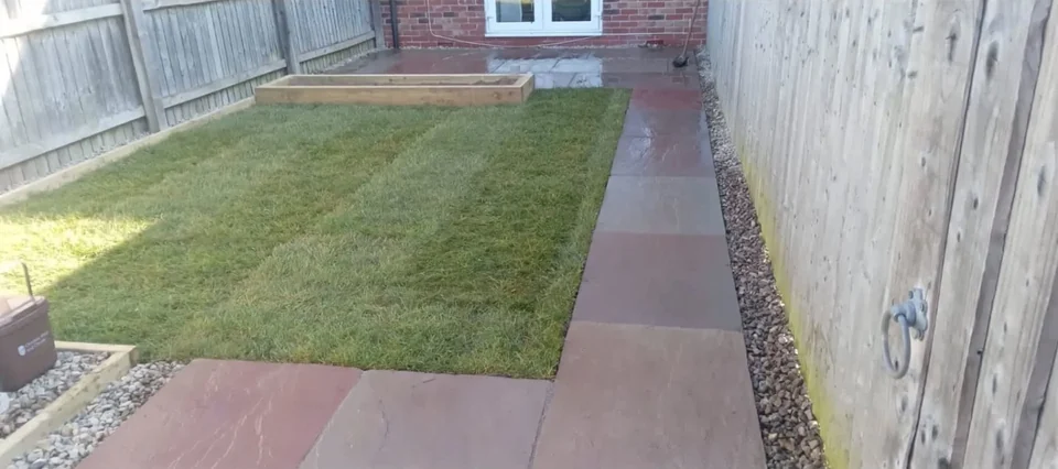 Narrow side garden landscaped with new lawn and paved path alongside the fence
