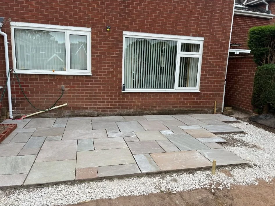 New sandstone patio being laid on a gravel base at the back of a house