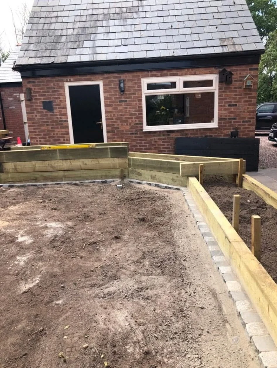 Timber sleeper raised beds being built around a prepared garden area