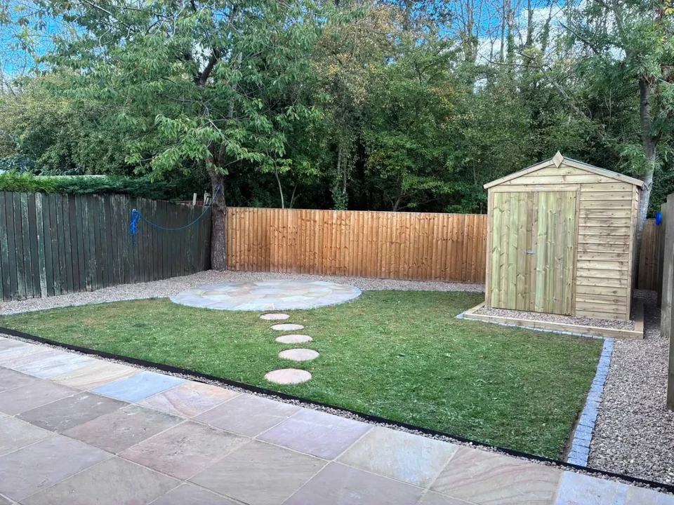 Landscaped back garden with lawn, stepping stones, circular patio, garden shed and new fencing