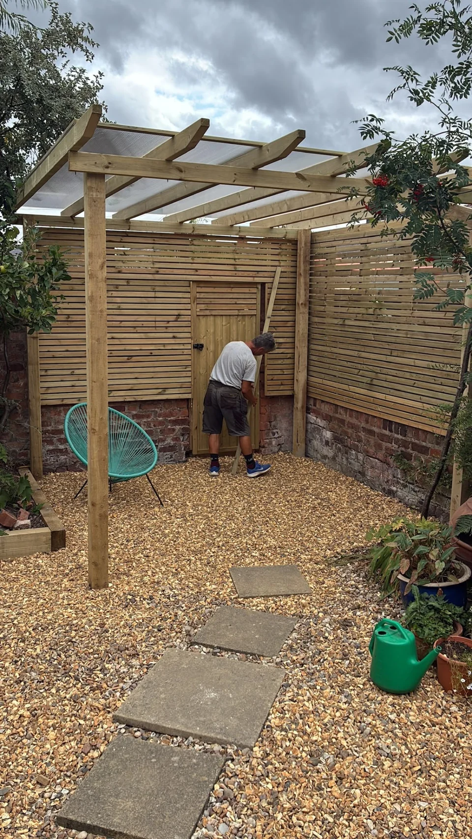 Timber pergola under construction over a gravel seating area