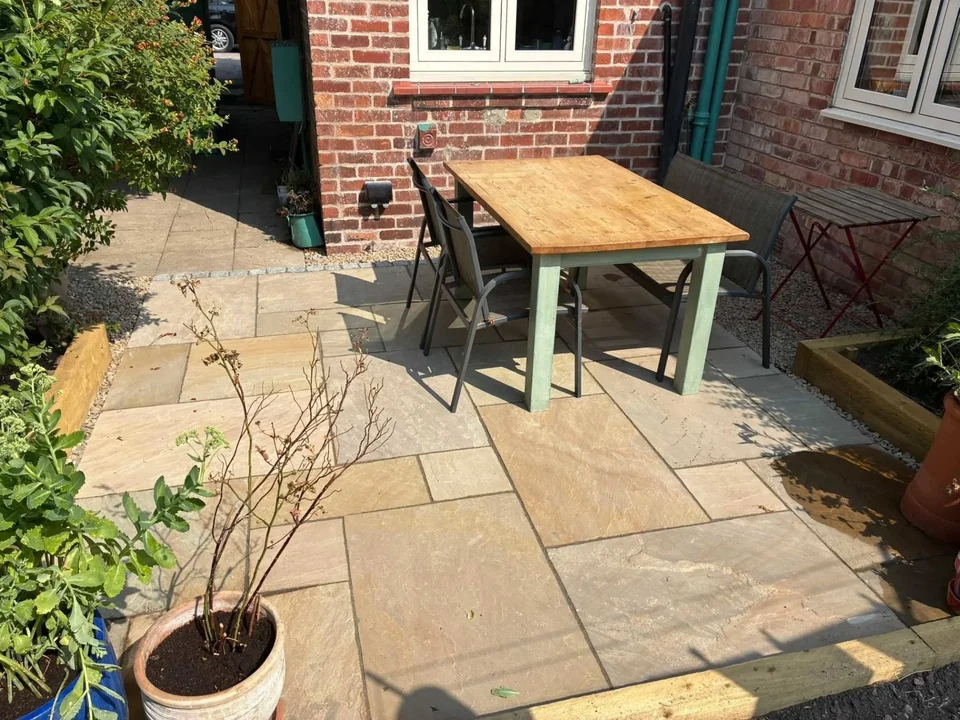 Sandstone patio with dining set, sleeper bed and potted shrub