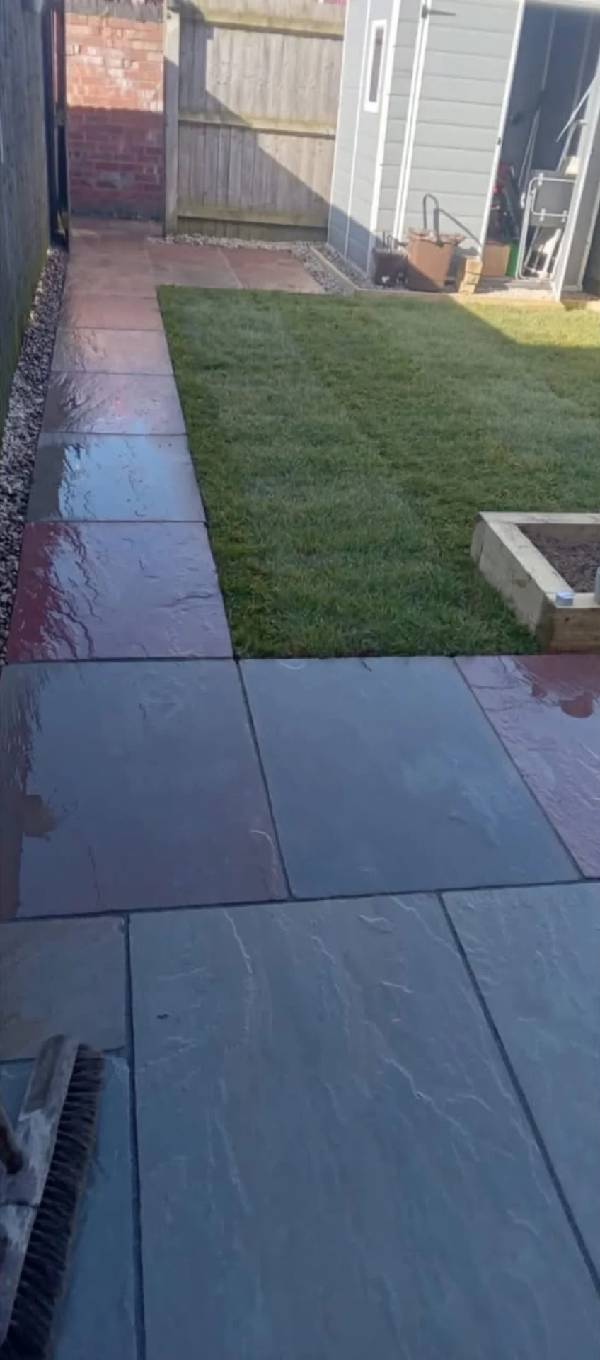 Dark slate paving path beside a new lawn in a narrow garden