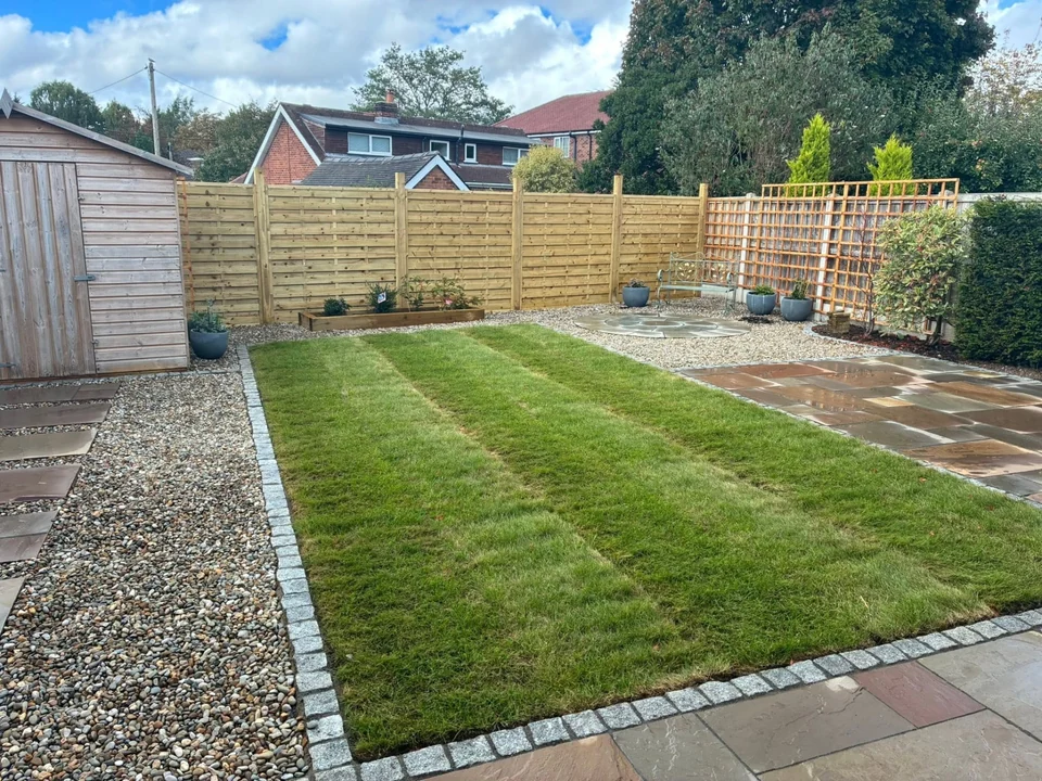 Freshly laid striped turf lawn with granite sett edging and gravel border