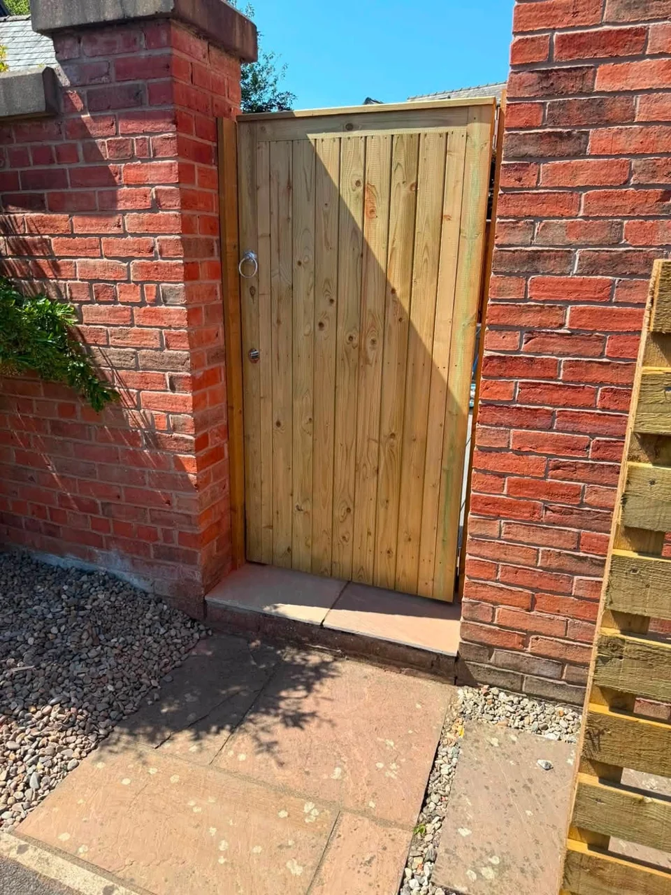 New timber garden gate fitted between brick pillars