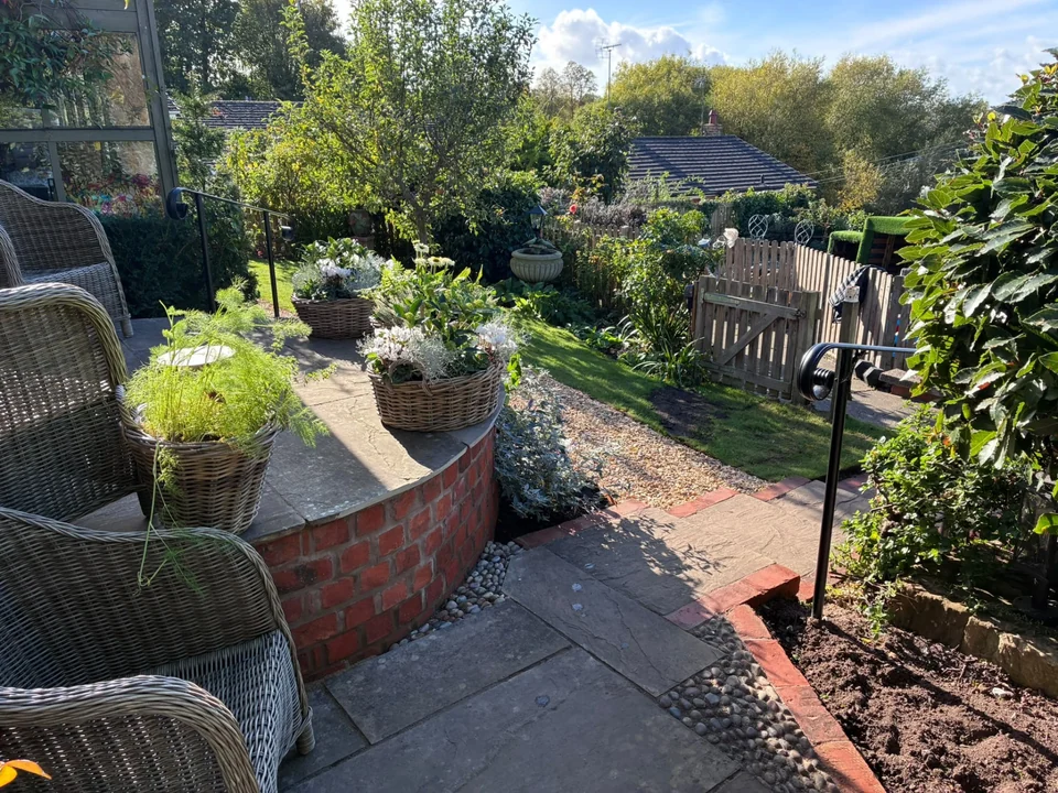 Hard landscaping with curved brick raised bed, paved seating area and gravel path