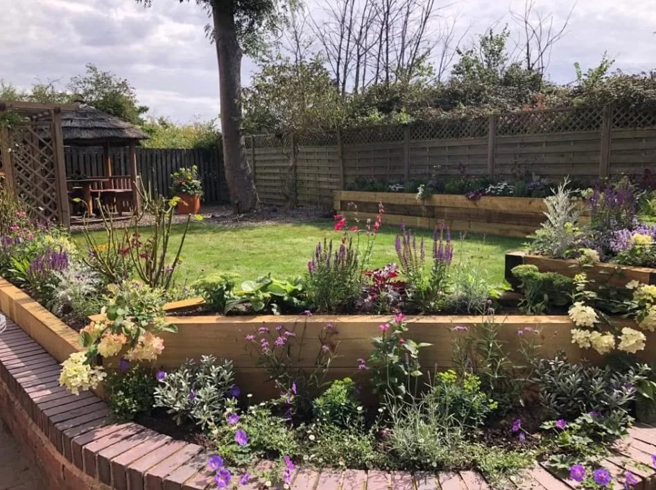Completed garden makeover with flowering raised brick border and sleeper beds