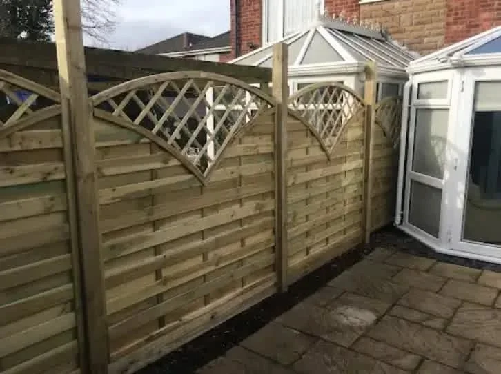 Decorative lattice-top timber fence panels beside a conservatory