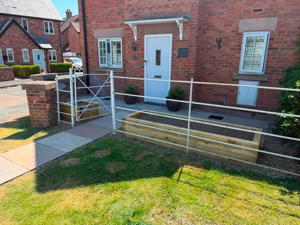 Front garden with sandstone path, railings, sleeper planter and lawn