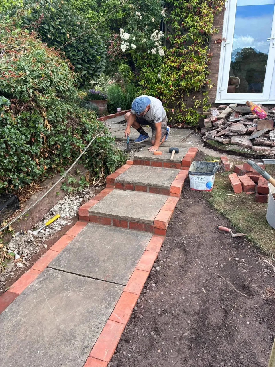 Landscaper laying brick-edged stone steps during a hard landscaping project