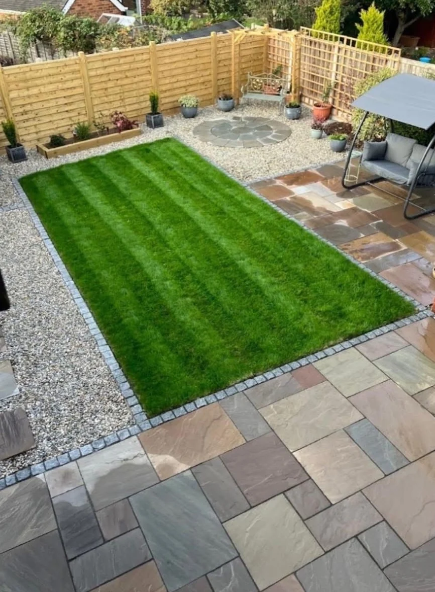 Landscaped garden with striped lawn, Indian sandstone paving, gravel borders and new fencing