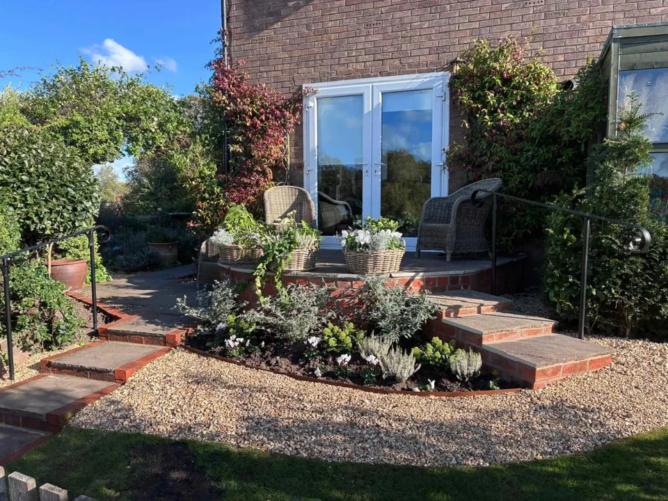 Front garden landscaping with brick-edged steps and planted borders by Chester Garden Services