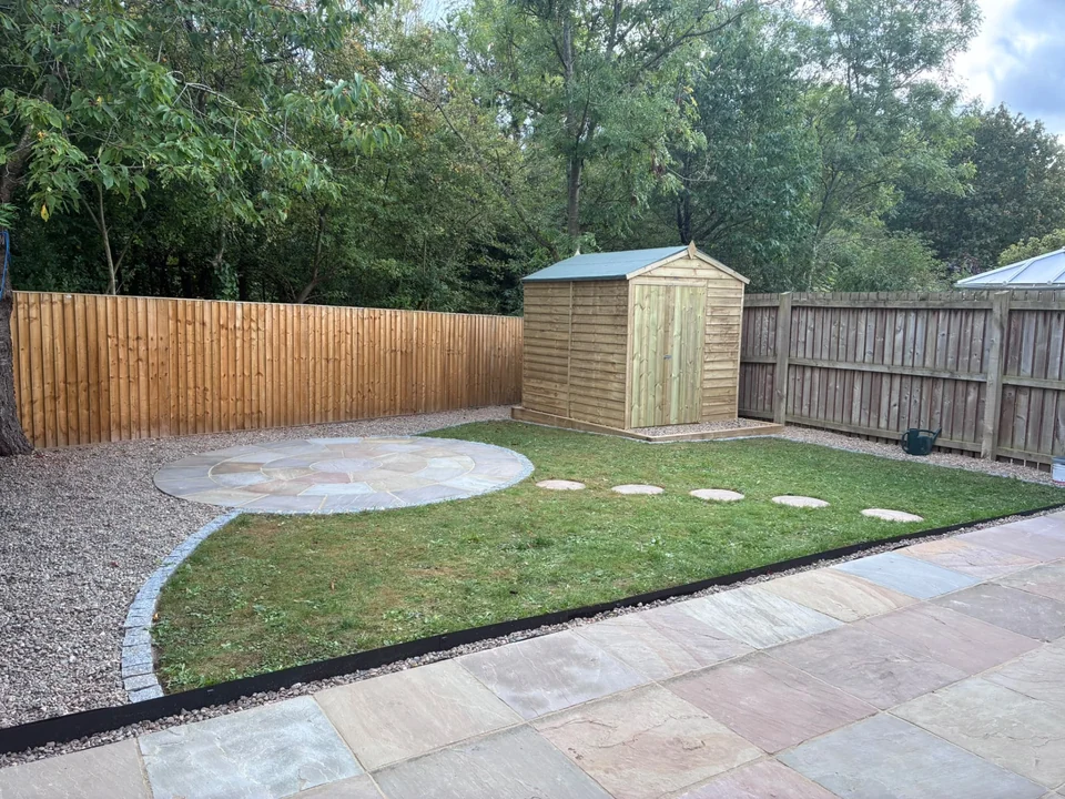 Completed garden with circular stone patio, stepping stones, lawn, timber shed and fencing